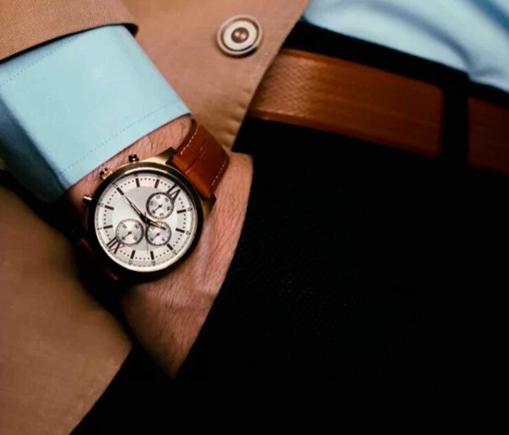Hombre luciendo reloj marrón de lujo en su muñeca - Homme Luxury Barbers