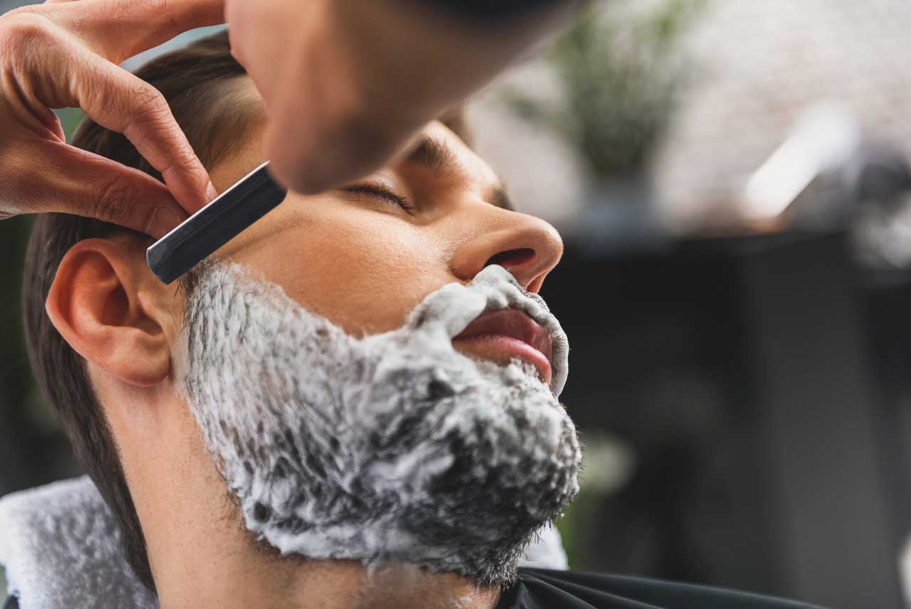 Hombre recortándose la barba en una barbería - Homme Luxury Barbers