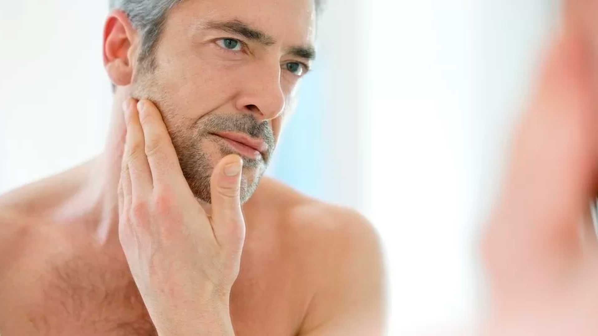 Hombre observando su rostro en el espejo - Homme Luxury Barbers