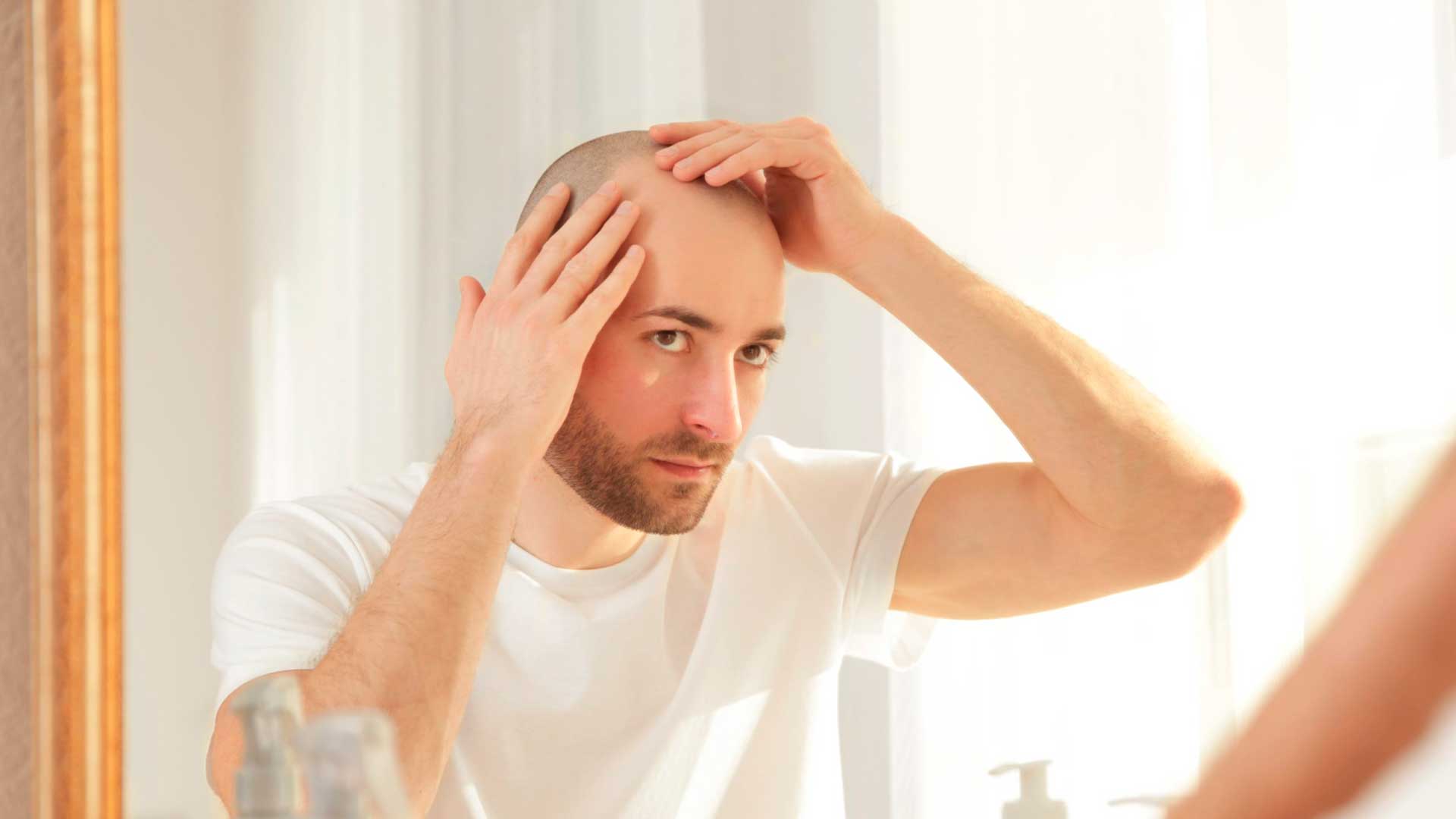 Hombre con la cabeza rasurada mirandose al espejo - Homme Luxury Barbers