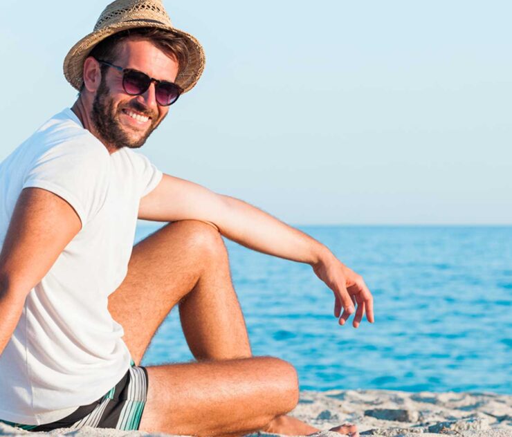 Hombres sentado sobre la arena a orillas del mar - Homme Luxury Barbers