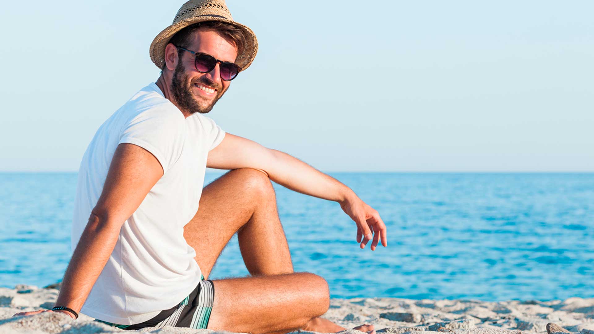Hombres sentado sobre la arena a orillas del mar - Homme Luxury Barbers