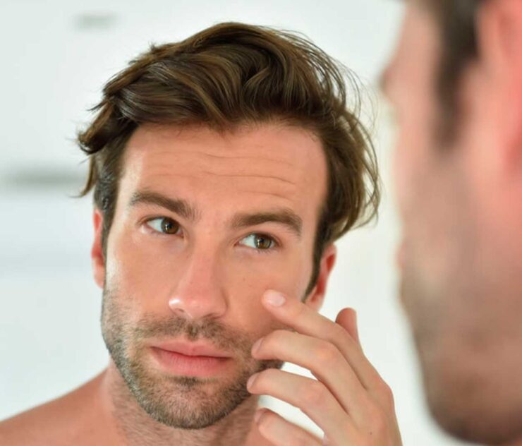 Rostro de hombre en primer plano mirándose al espejo - Homme Luxury Barbers