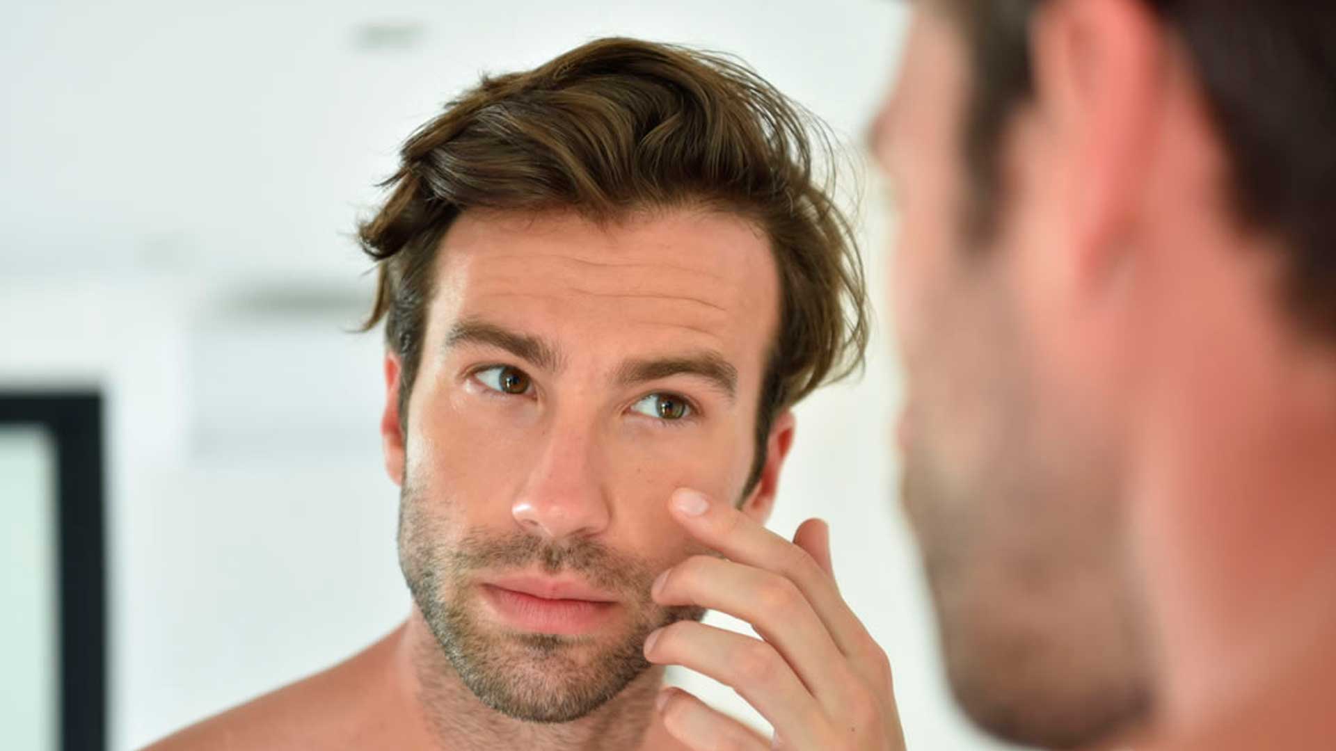 Rostro de hombre en primer plano mirándose al espejo - Homme Luxury Barbers