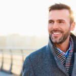 Hombre con ropa de invierno, sonriendo al aire libre - Homme Luxury Barbers