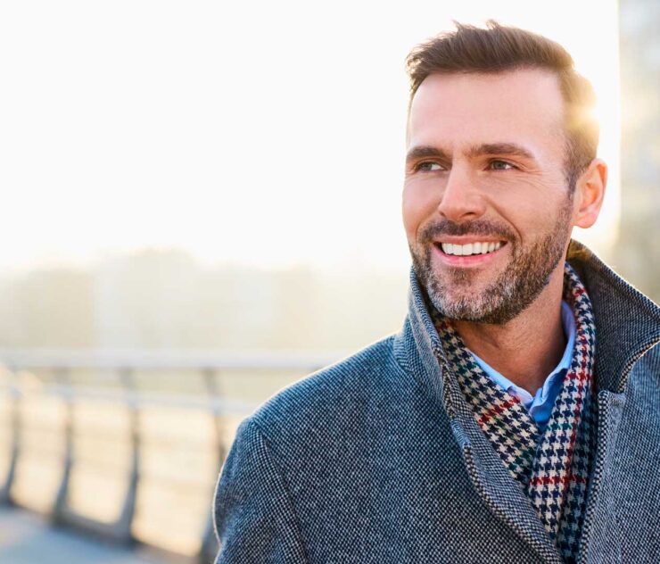 Hombre con ropa de invierno, sonriendo al aire libre - Homme Luxury Barbers