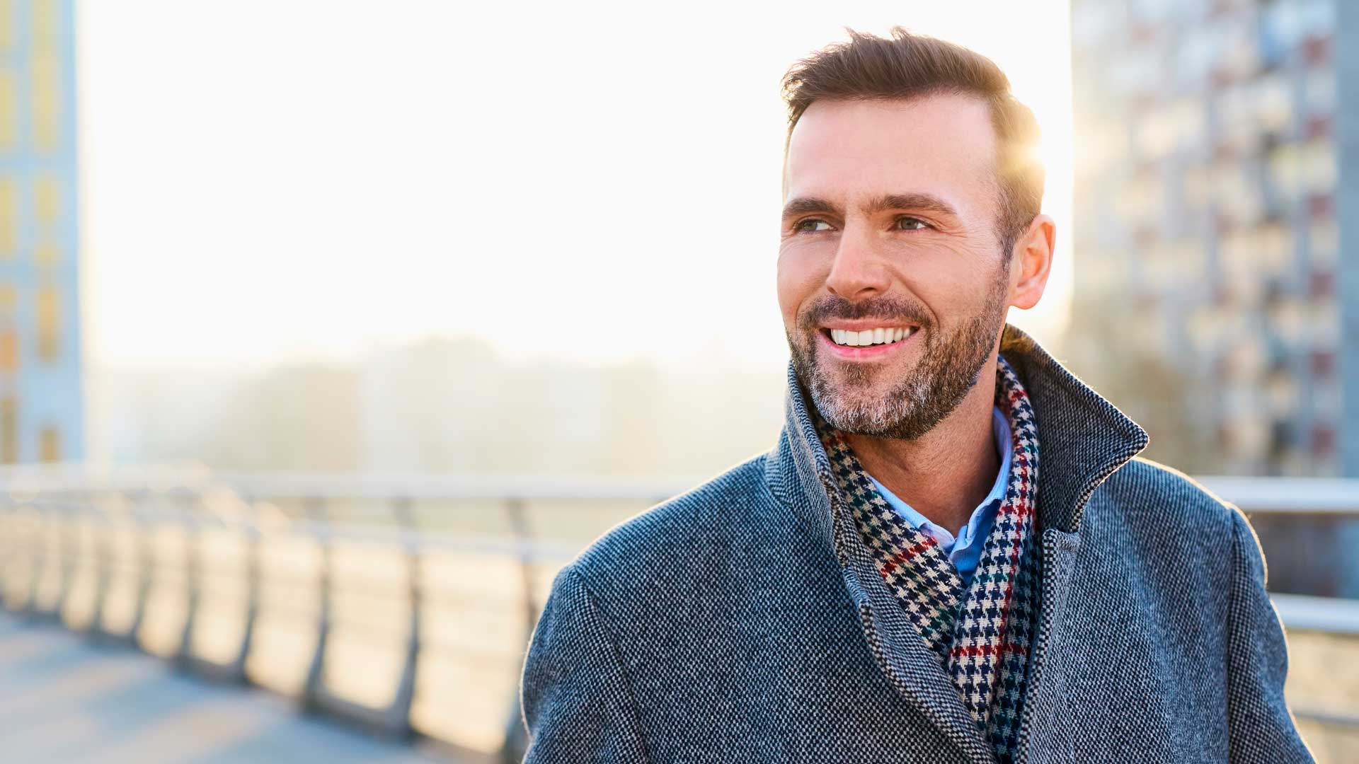 Hombre con ropa de invierno, sonriendo al aire libre - Homme Luxury Barbers