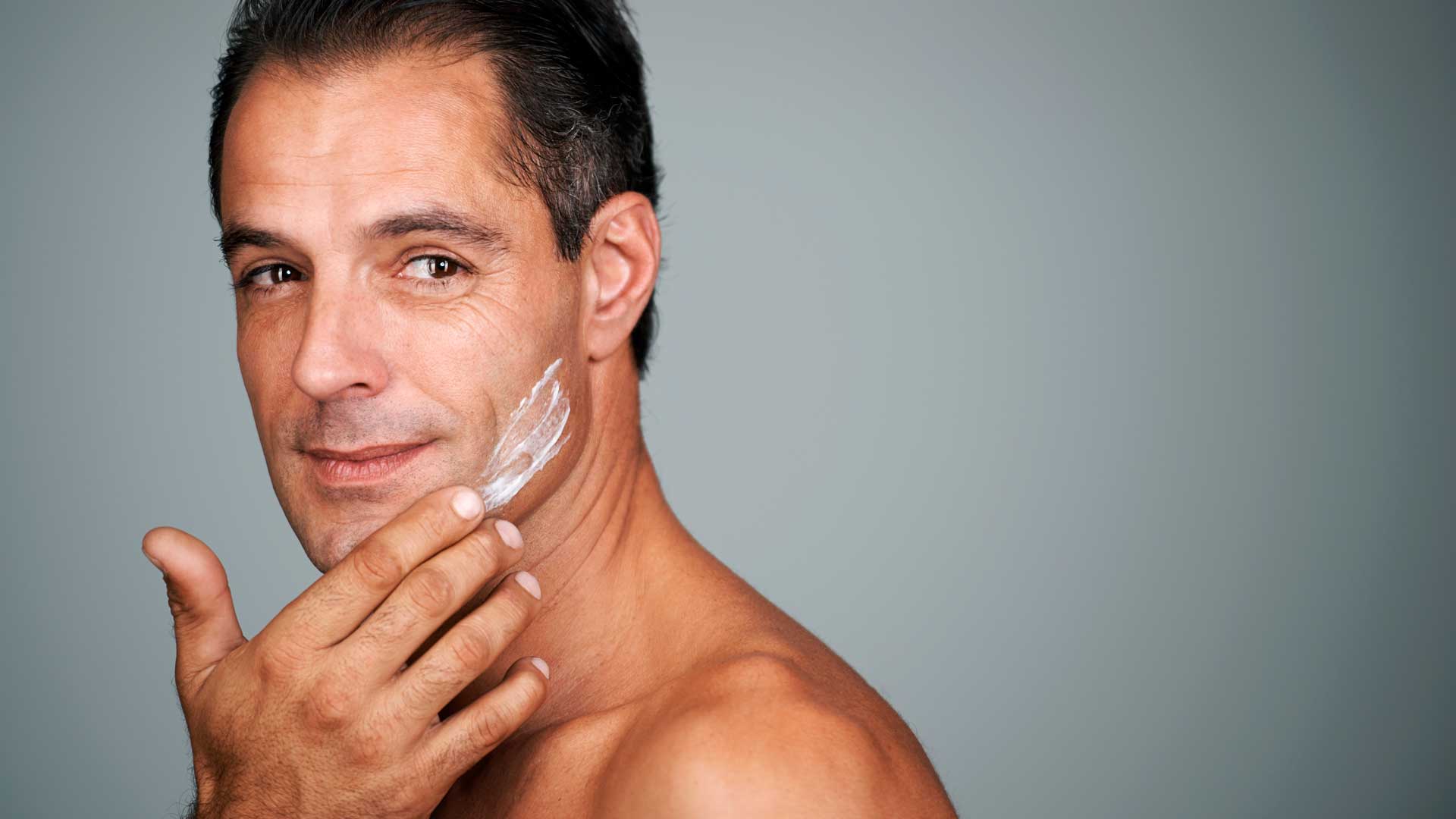 Hombre de mediana edad aplicándose crema facial - Homme Luxury Barbers