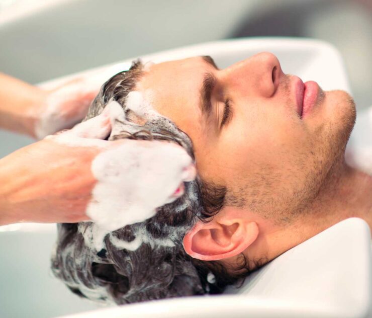 Manos lavando el cabello de un hombre.